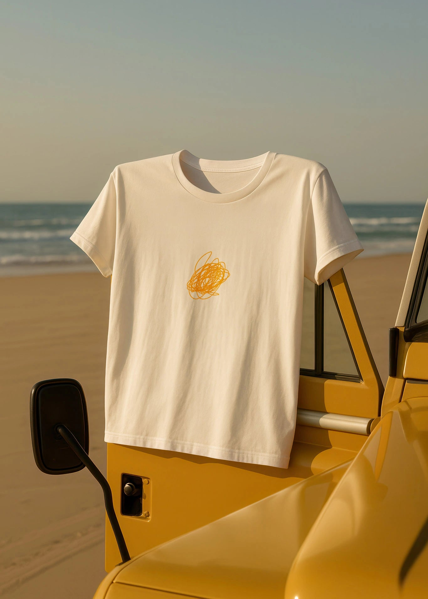 White t-shirt with a yellow graphic on a yellow vehicle at the beach