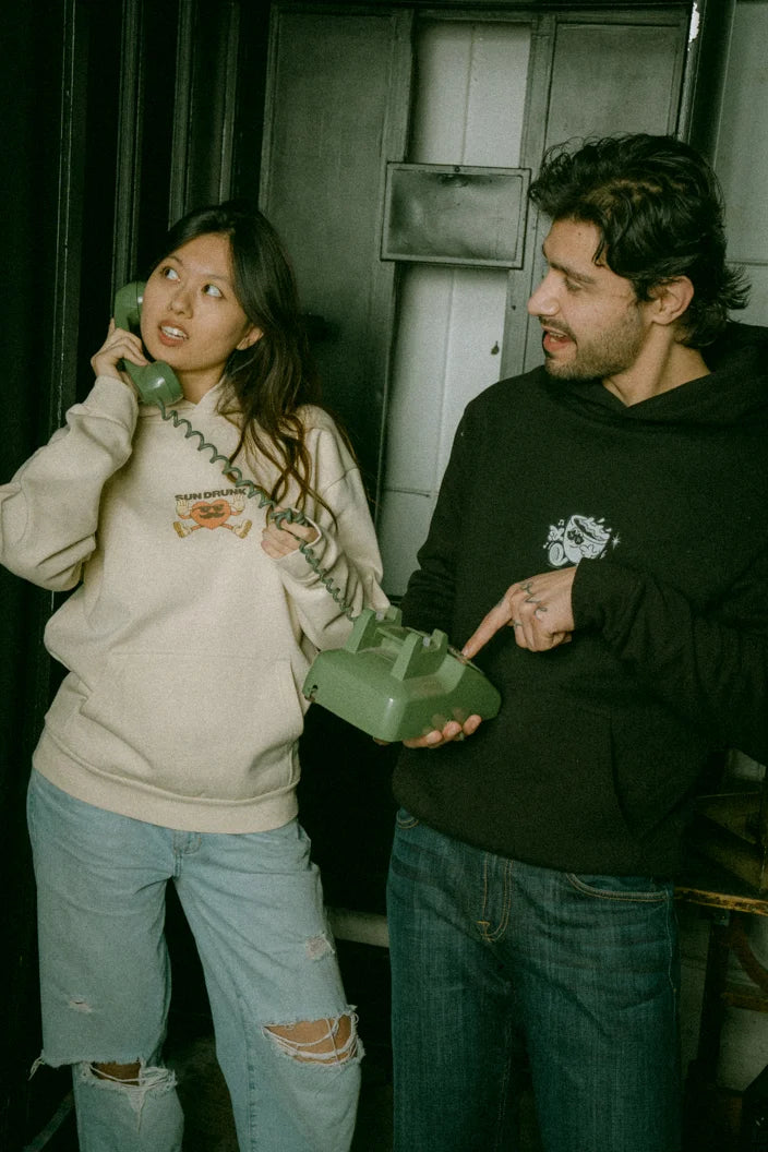 man and women wearing soft boxy heavyweight hoodies with designs 'Sundrunk' and 'The Day Awaits'