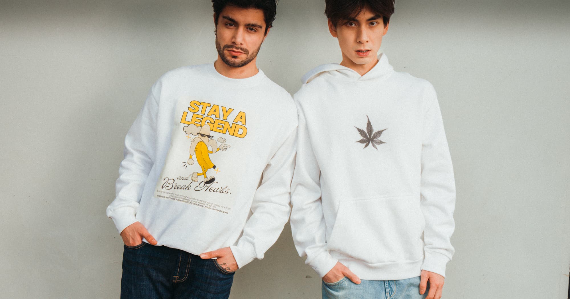 Man wearing white heavyweight  cotton graphic sweatshirt 'Stay a Legend' and man wearing graphic plant hoodie